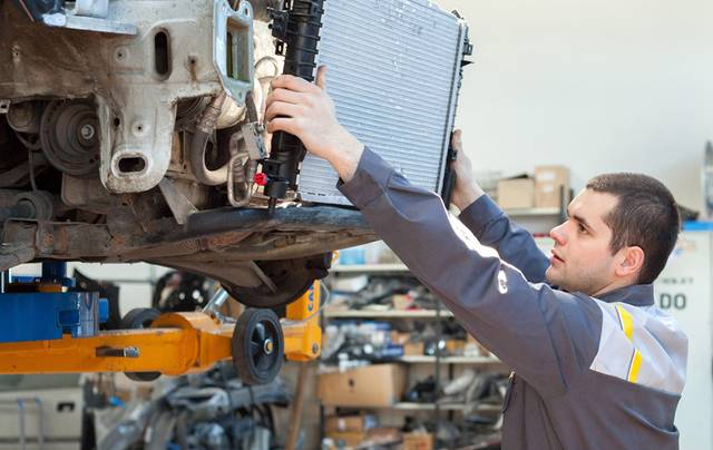 Mechanic replacing a car radiator