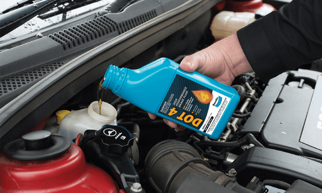 a person filling up their vehicle with brake fluid